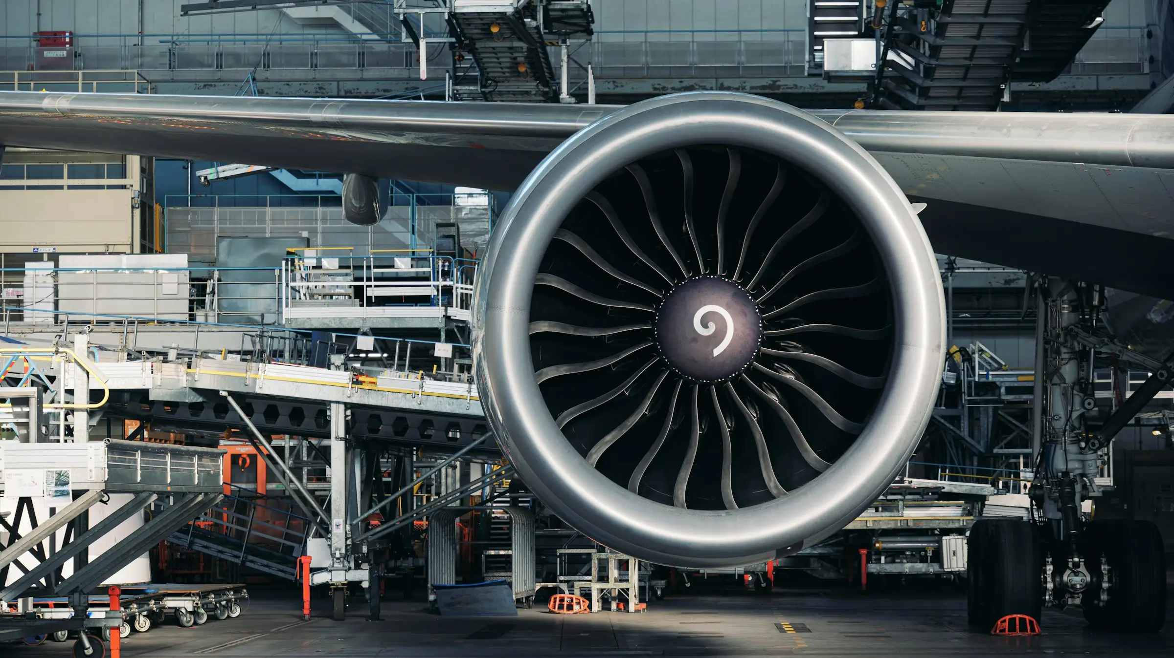 Jet engine mounted under an aircraft wing in a maintenance hangar