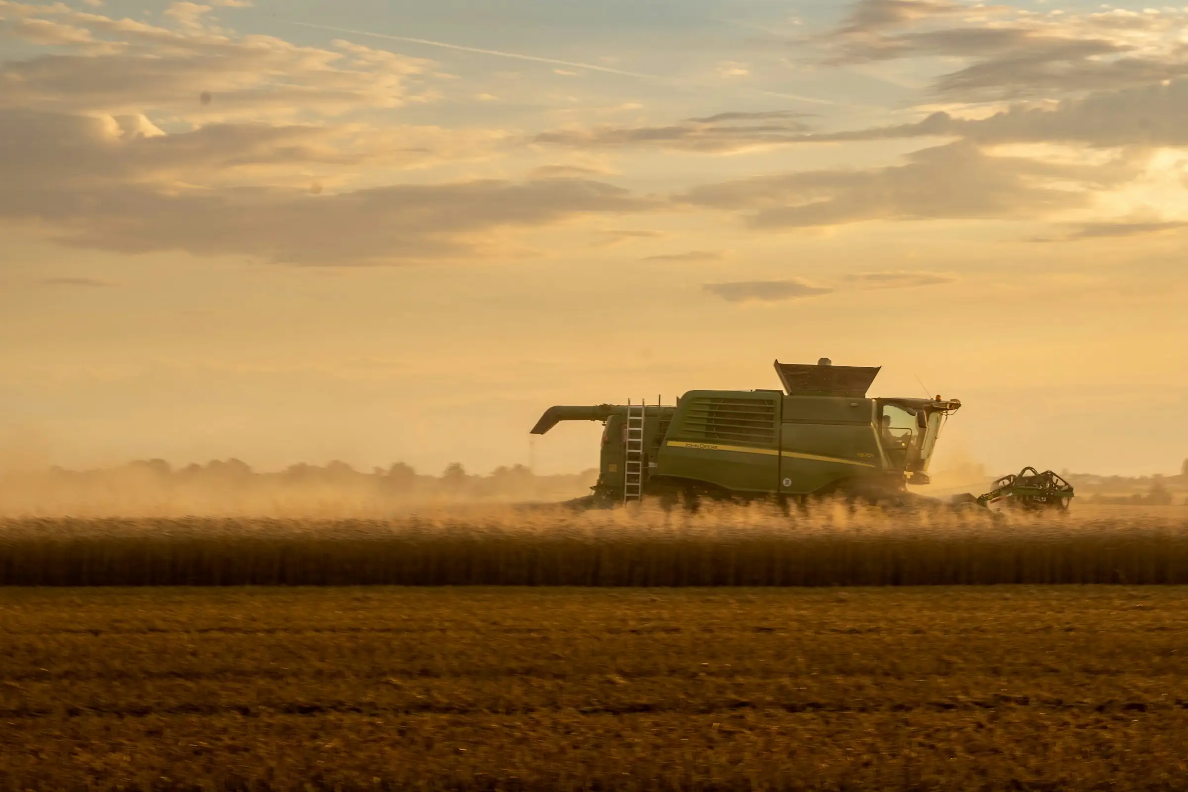 Combine harvester working a grain field at golden hour