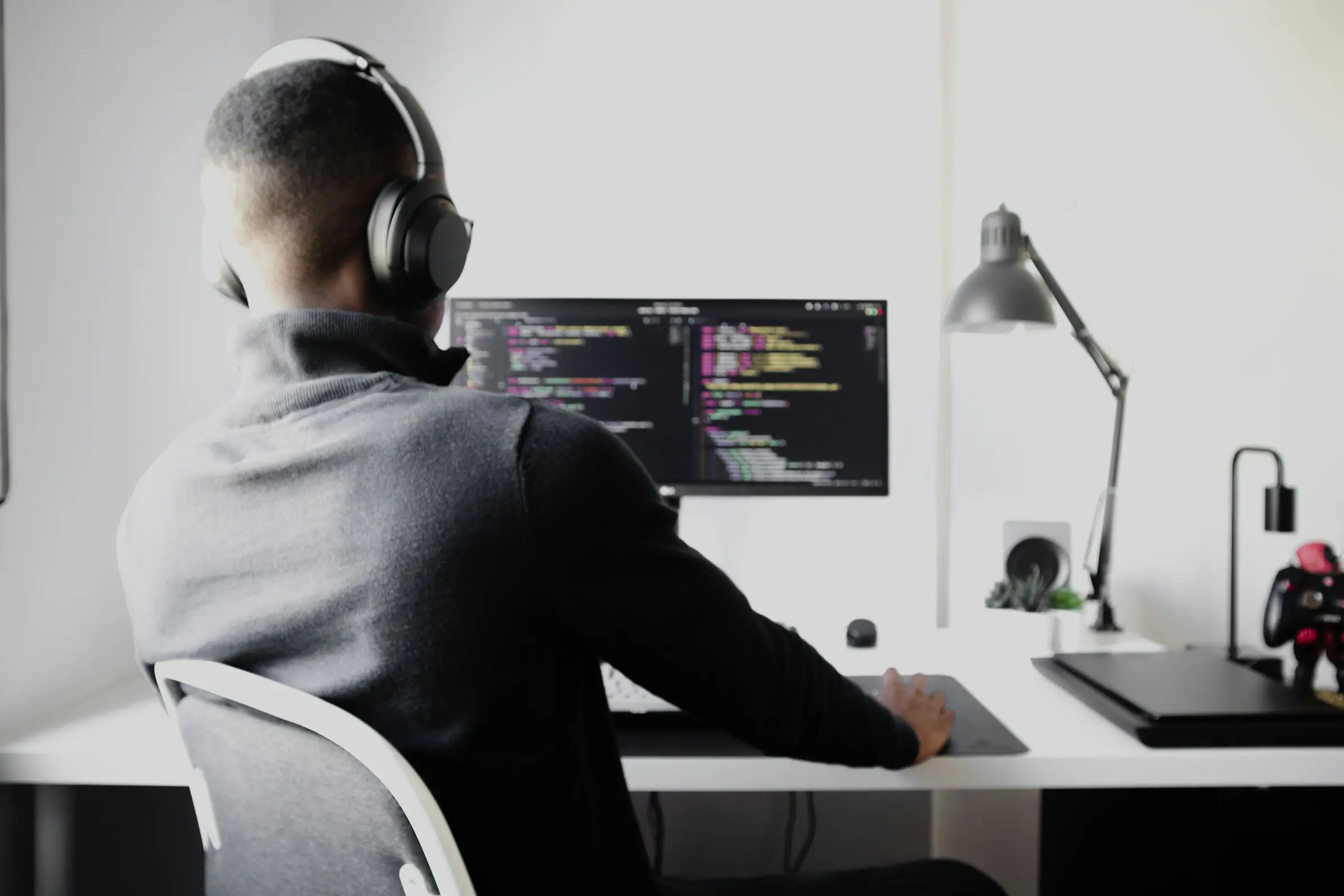 Developer in headphones writing code on a desktop monitor