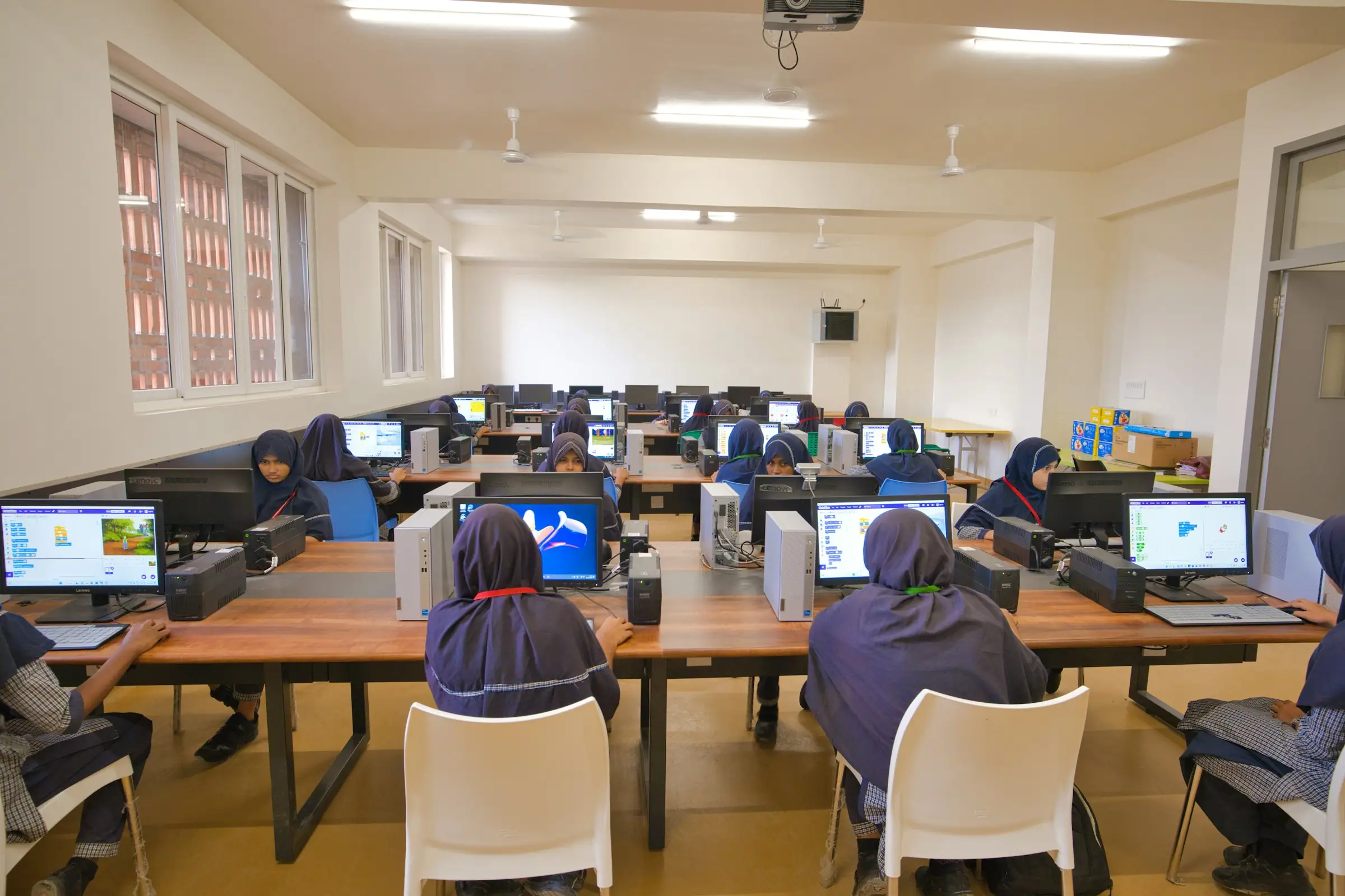 Students working at desktop computers in a bright school computer lab