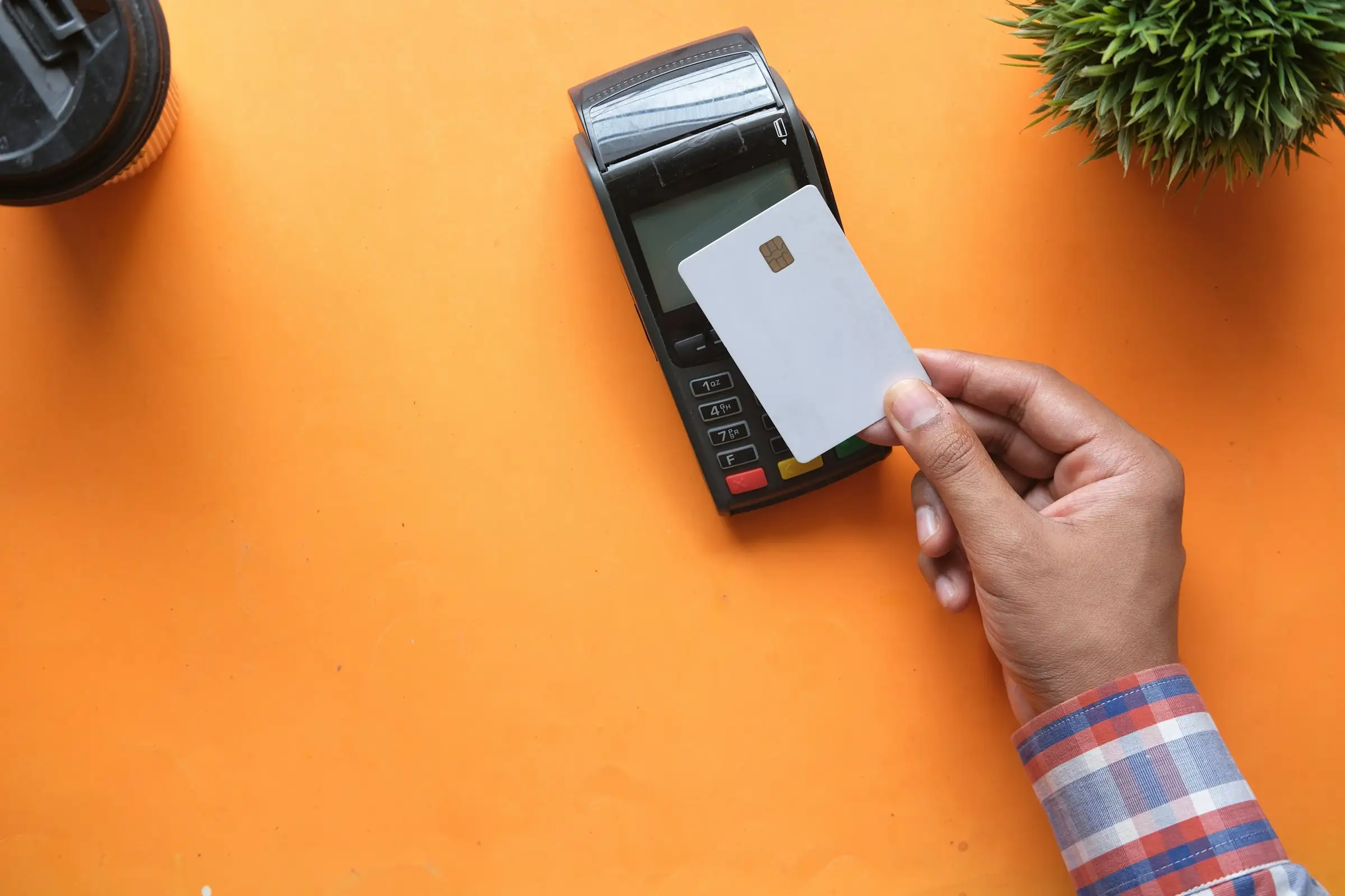 Hand inserting a blank card into a card payment terminal