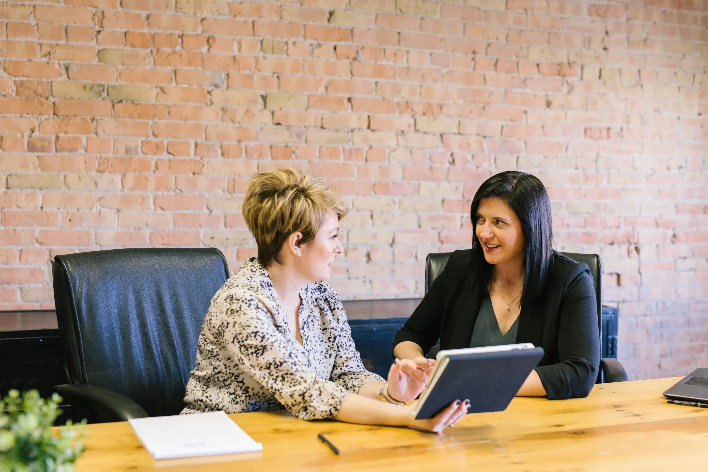 Two colleagues reviewing information on a tablet at an office meeting table
