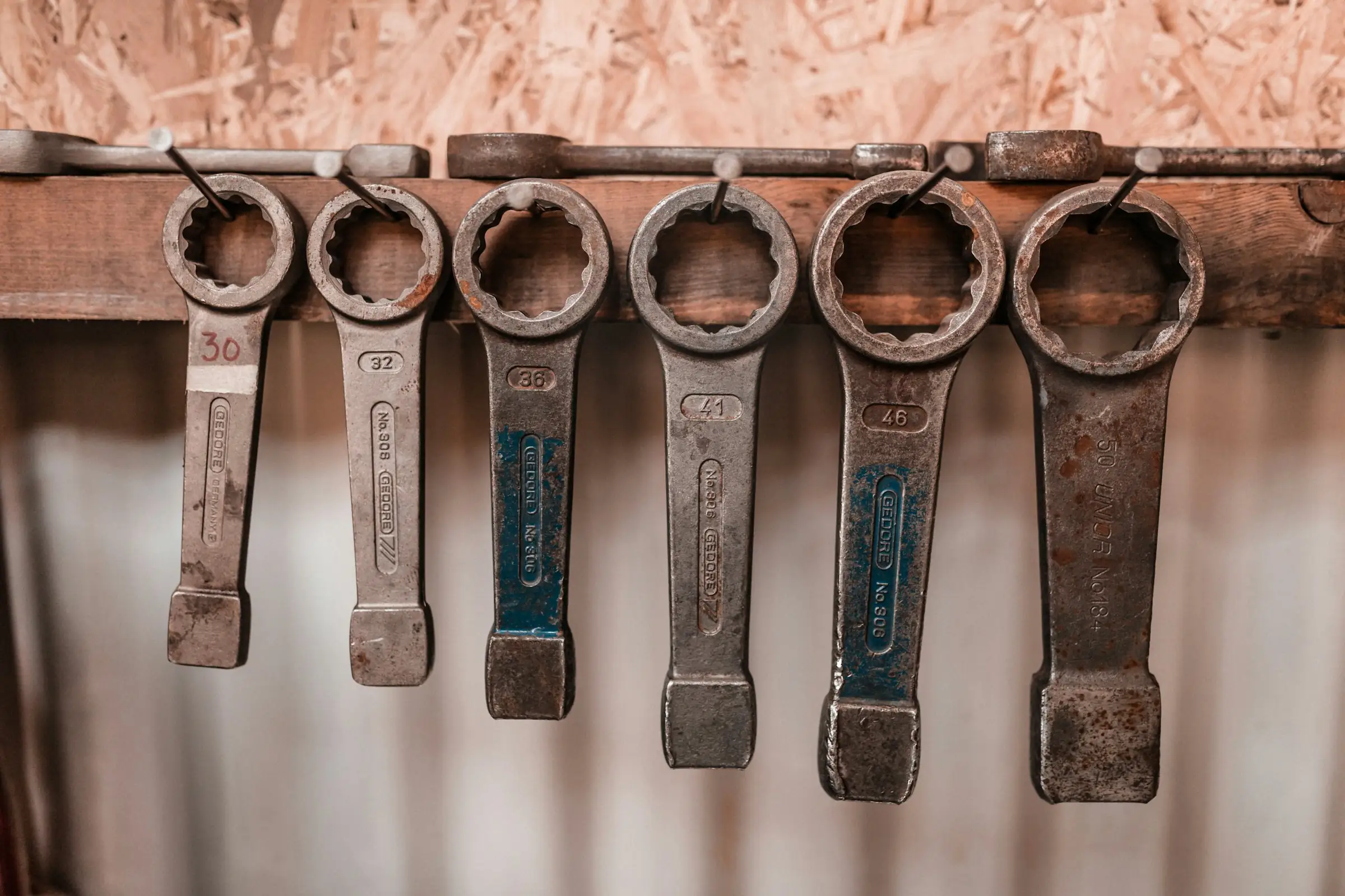 Row of heavy ring spanners hanging on a workshop rail