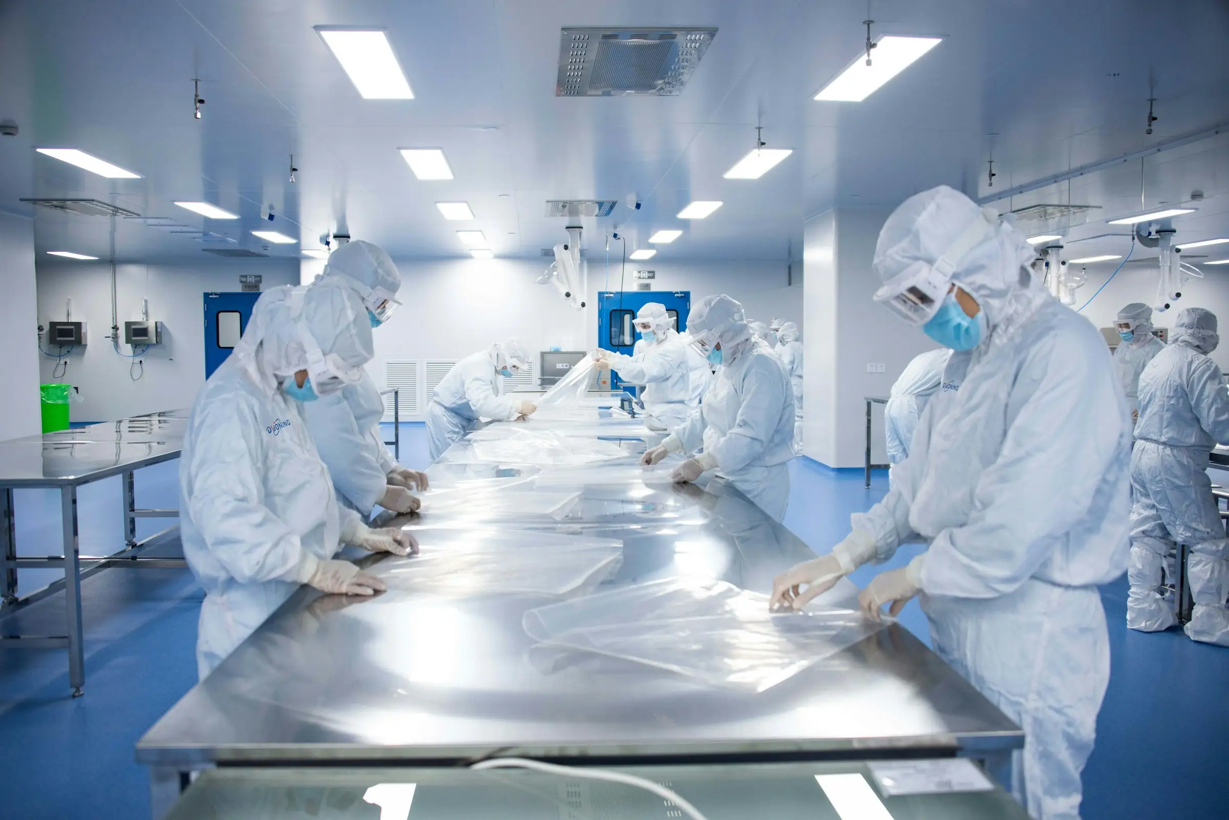 Workers in cleanroom suits on a pharmaceutical production floor